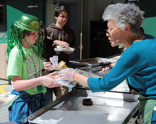 Dustin Ledbetter (left), 12, receives a burger from “Grandma Neu” on St. Paddy’s Day during the barbecue lunch at Idyllwild School.                                                     Photo by Jenny Kirchner 