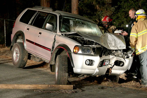 According to California Highway Patrol Officer Mike Murawski (center), at least two passengers and a driver were traveling south on Fern Valley Road about 10:10 p.m. Wednesday, Feb. 26, when the driver appears to have lost control of the vehicle which hit a tree head-on. Idyllwild Volunteer Fire Company Firefighter Steve Friemoth (left), Murawski and Idyllwild Fire Chief Patrick Reitz (right) inspect the Mitsubishi Monte Sport.  Allegedly, the driver fled the scene on foot, however, that was not been confirmed at the scene. The cause of the crash is still under investigation. Idyllwild Fire transported both occupants to Desert Regional Medical Center with unknown injuries, according to IFPD Capt. Mark LaMont. Photo by Jenny Kirchner