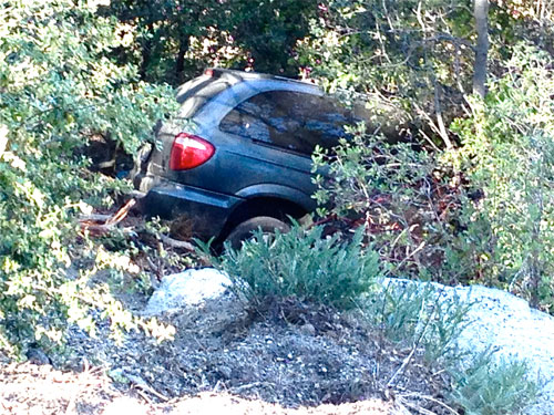 At right, on Wednesday morning, May 21, a minivan driven by Mary Davis of Twin Pines went about 60 feet over the very steep side of Highway 243 about a mile north of the Forest Service Alandale Station. She was entirely unhurt. Davis said her car began to slide and went over nose first, and she just drove it straight down the slope with manzanita slowing her to a stop. Her work friend, Cindy Hansen, arrived to take her into Idyllwild where both women work as caregivers. Emergency vehicles responding included Cal Fire Engine 23 from Pine Cove, Idyllwild Fire, Forest Service, California Highway Patrol, Riverside County Sheriff and Idyllwild Garage.  Photo by Jack Clark