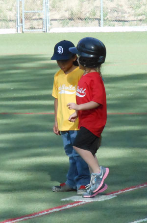 T-ball players from the Padres (in yellow) and the Angels (in red) greet each other on first base. Photo by Teresa Garcia-Lande