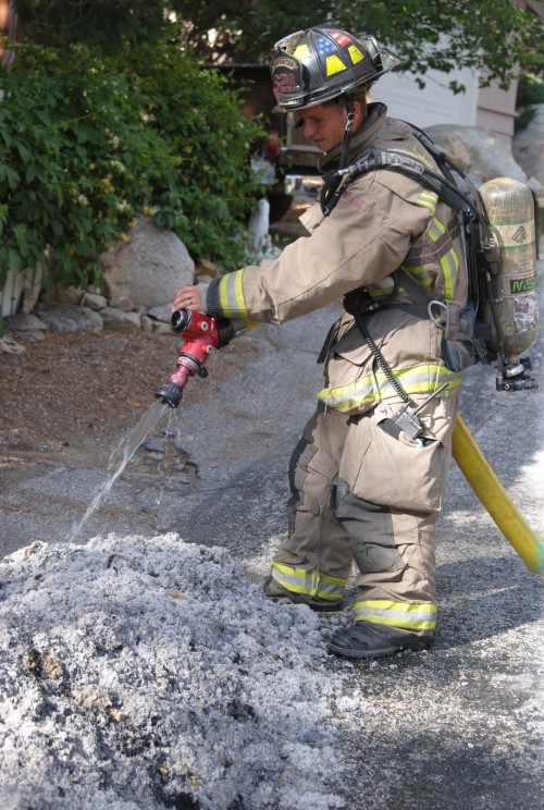 Firefighter Greg Minor extinguishes the burning cellulose insulation from a home on Rim Rock