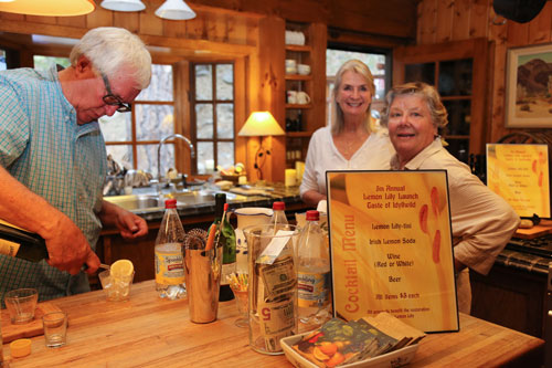 At bottom, Scott Fisher (left), of this year’s Lemon Lily Festival committee, prepares a Lemon Lily soda during the Lemon Lily Launch Taste of Idyllwild which Erin O’Neill (center) hosted. Beth Darling (right) watches Fisher’s careful bar keeping.  Photo by Cheryl Basye