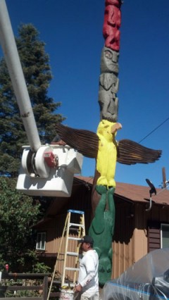 TOTEM RETOUCHED: Antonio, the painter, repaints Shane Stewart’s totem pole on the east side of Highway 243 in Pine Cove on Monday. Bill Butler carved the pole in 1948 and it still stands today. (See past tense for an older photo.)                   Photo by Jay Pentrack 