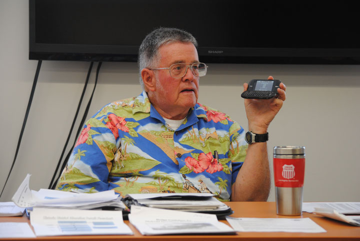 Warren Monroe, chair of the Local Review Board for the Idyllwild Historic Preservation District, holds his phone up for the entire board to hear applicant Paul White discuss his property. Minutes later, White and his wife Katherine arrived at the board meeting in person.  Photo by J P Crumrine