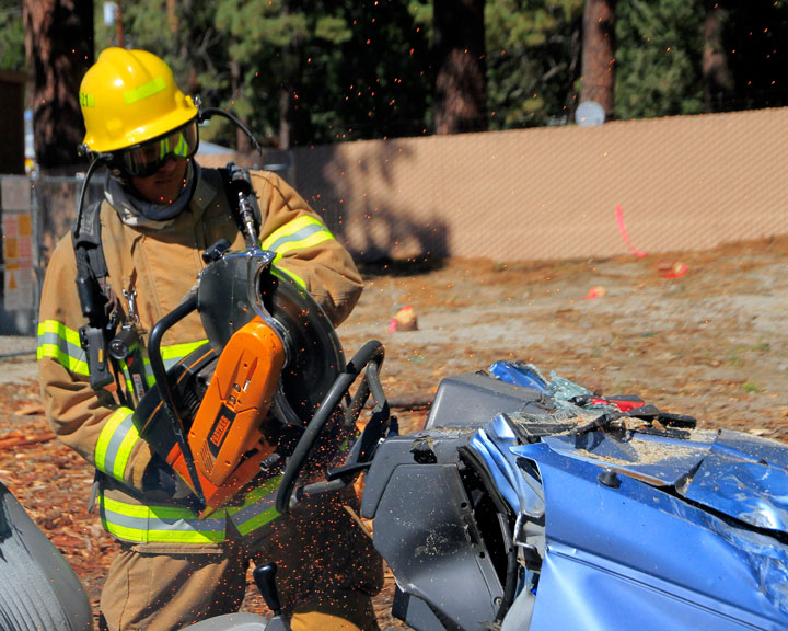 IFPD OPEN HOUSE: Idyllwild Firefighter Nelson Escobar saws at the steering wheel demonstrating life-saving equipment at the Idyllwild Fire Department’s open house Saturday.                                            Photo by John Drake 