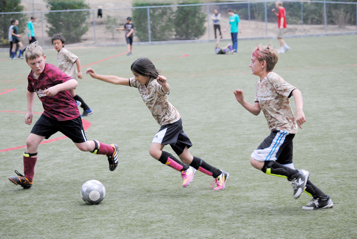 Hannah Lady and Austin Gooch (right) of the Suburban Sand Dragons try to get past Joseph Tiso of the Pine Cove Market Crimson Tide in the 9-11 year old Town Hall soccer championship game held Thursday at Idyllwild School. In the end, the Suburban Sand Dragons went home with the win.   Photo by Teresa Garcia-Lande