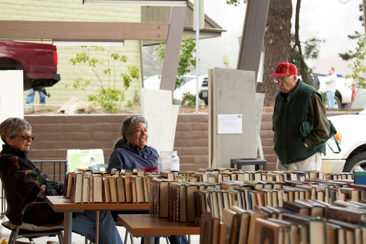 Marsha Lytle (right) and Joy Woodman (center), volunteers for the Friends of the Idyllwild Library, were trying to keep warm during the annual Memorial Day weekend book sale while David Leusch examines the books. Photo by John Drake