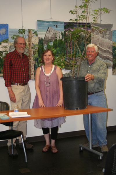 Idyllwild Lilac Festival Founder Gary Parton (right) presents an Ernie Maxwell Lilac tree to Town Crier Co-owner Becky Clark after Idyllwild Area Historical Society Historian Bob Smith’s (left) talk on Maxwell, founder of the Town Crier. The presentation occurred Saturday at the Idyllwild Library. The lilac will be planted at the Town Crier’s office on North Circle Drive. Another will be planted at the IAHS museum grounds while Parton has one at Alpenglow Gardens in Fern Valley. Photo by Jack Clark 