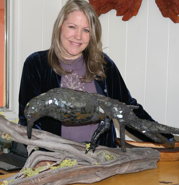 Linda Lauderbaugh in her Idyllwild “Over the Rainbow” gallery displays her newest favorite art medium — a black, recycled glass raven.Photo by Marshall Smith 