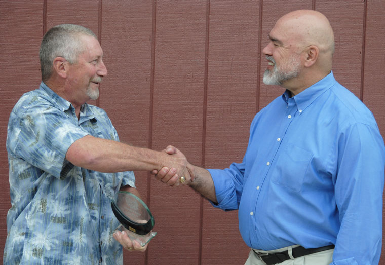 Robert Hewitt, vice president of the Pine Cove Water District, hands a plaque to retiring Board President Michael Esnard after his last meeting last week. Photo by J.P. Crumrine