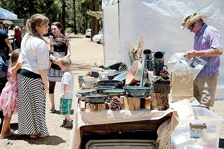 Les Walker (right) wraps one of his handmade ceramic pieces in June 2014 at the 2nd Saturday Art Fair held at the Idyllwild Community Park. Photo by Jenny Kirchner