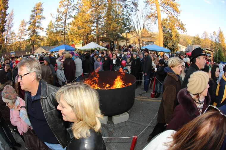 Despite the cold temperatures Saturday, the throng attending the Tree Lighting Ceremony warm themselves next to the fire, which Rob Muir and his mother Marge lit.