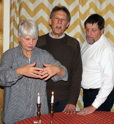 Temple Har Shalom officers President Pat Schnetzer (left), Event Logistic Coordinator Jeffrey Cohen, (center) and Barry Zander, secretary and fundraiser, enact the lighting of the Shabbat candles. Zander pointed out that observing Shabbat is the center of Jewish observances, and the only one mentioned in the Ten Commandments, “Remember the Sabbath Day, to keep it Holy.” Photo by Marshall Smith 