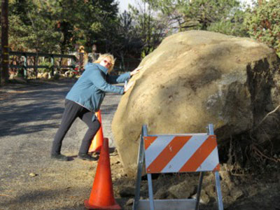 Corrine Brown tries to move the rock that slid onto her street in Idyllwild during last week’s rain storm.Photo by Ray Brown 