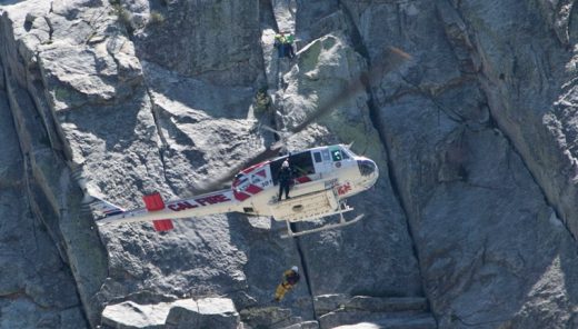 A male climber was rescued from Lily Rock Sunday afternoon, May 22, after complaining of chest pain while rock climbing. The patient was able to belay down to solid ground where firefighters assisted him, preparing him to be hoisted into Helicopter 301. Here one of the helicopter crew descends to help prepare the climber to be hoisted up and transported for further medical aid. Rock climbers unrelated to the incident can be seen in the background just above the helicopter. At the ambulance, the patient refused transport to a medical center.Photo by Jenny Kirchner 