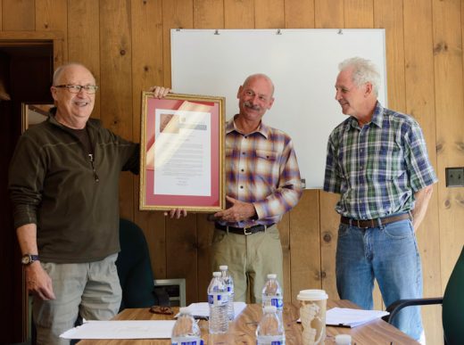 General Manager Steve Erler (center) received proclamations from Jeff Stone, California state senator, and Chuck Washington, Riverside County supervisor, and a plaque from members of the Fern Valley Water District on his retirement from 22 years of service. Here, Director Richard Schnetzer (left) helps Erler hold up Stone’s proclamation, while board President Jim Rees reads it to the other board members.Photo by Tom Kluzak 