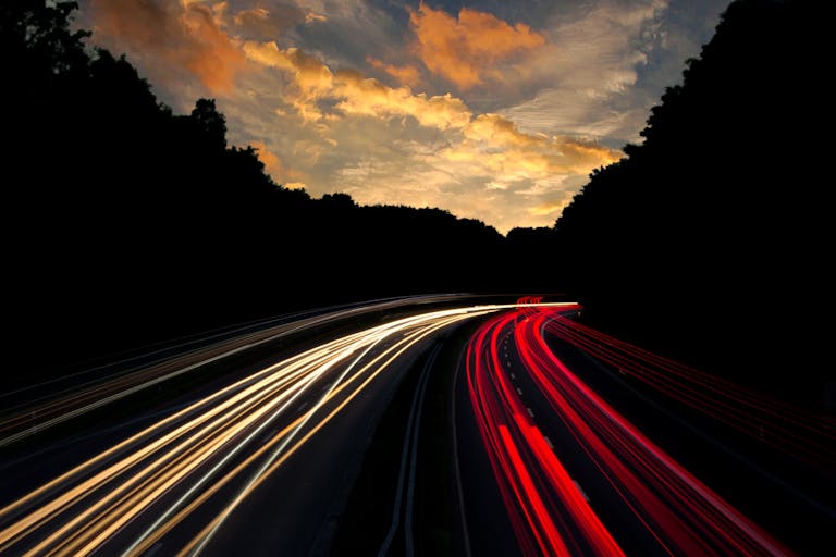 Dramatic long exposure of highway light trails beneath colorful twilight sky in Mönchengladbach, Germany.