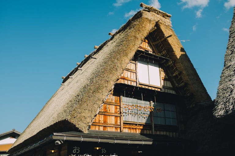 Gorgeous shot of a traditional Japanese thatched roof house under a clear blue sky.