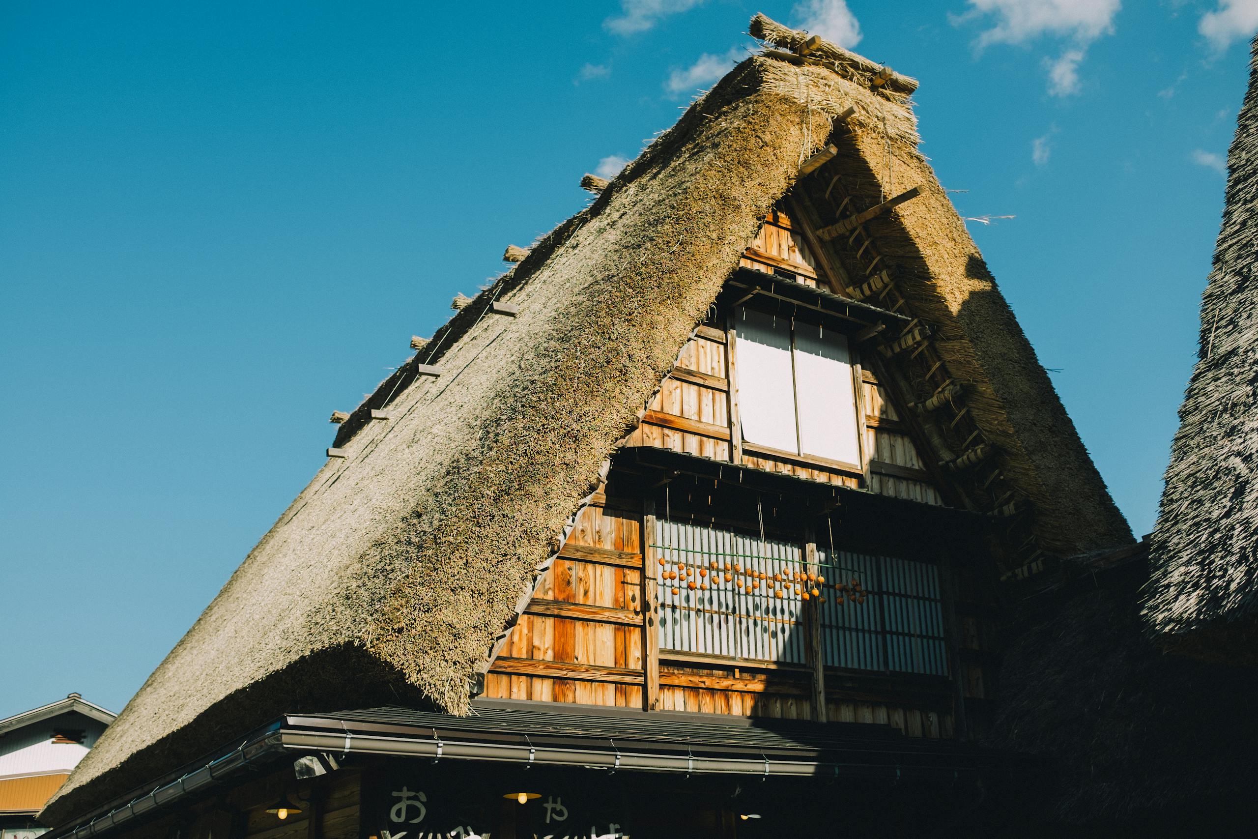 Gorgeous shot of a traditional Japanese thatched roof house under a clear blue sky.