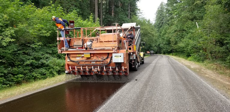 Chip seal process being applied to a rural road in Vida, Oregon.