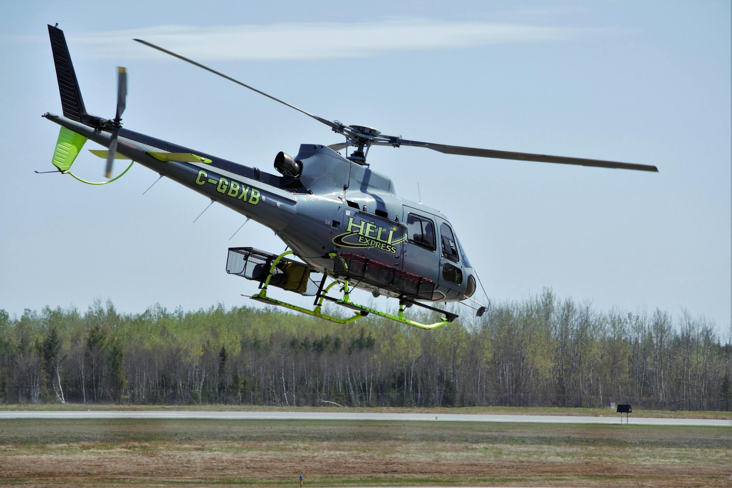Helicopter mid-flight over a forest on a clear day, showcasing agility and speed.