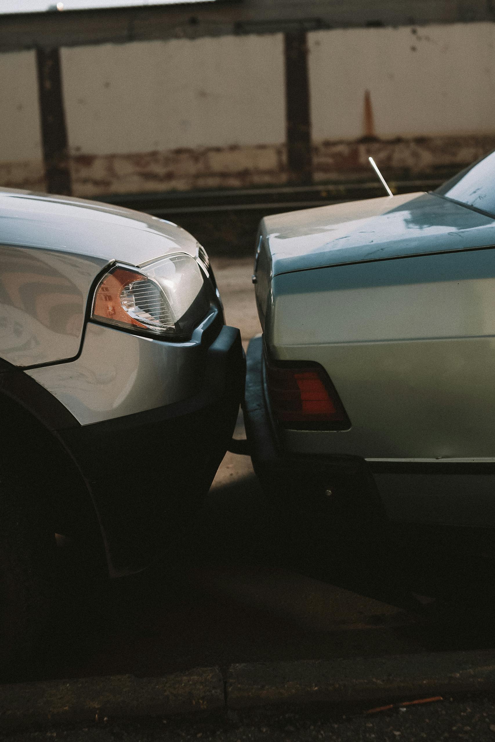 A close-up view showing the aftermath of a rear-end car collision in an outdoor setting.