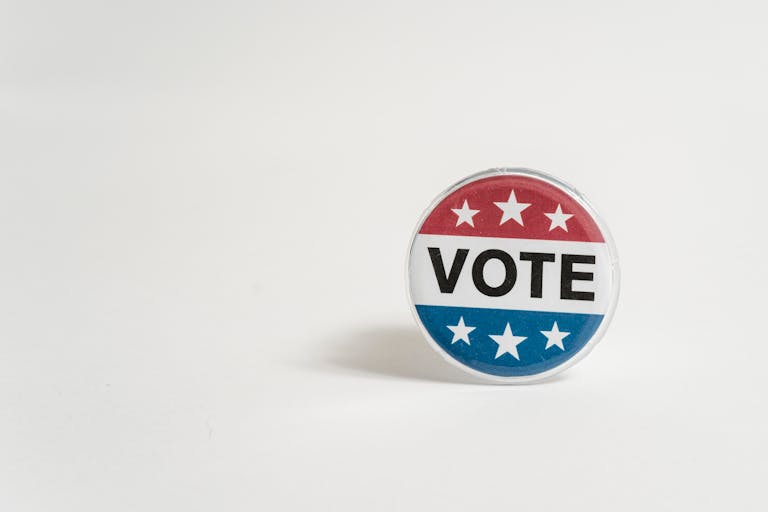 Close-up of a red, white, and blue vote button with stars on a white background.