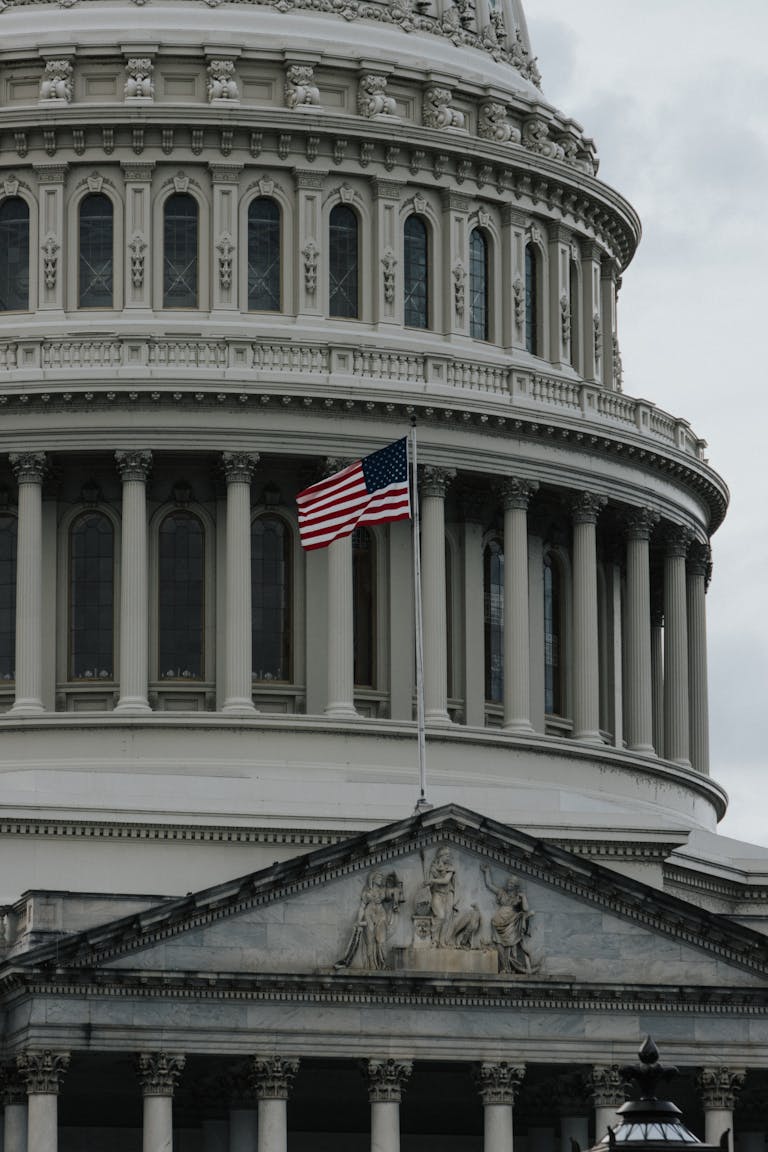 Close-up of the United States Capitol with American flag waving outside.