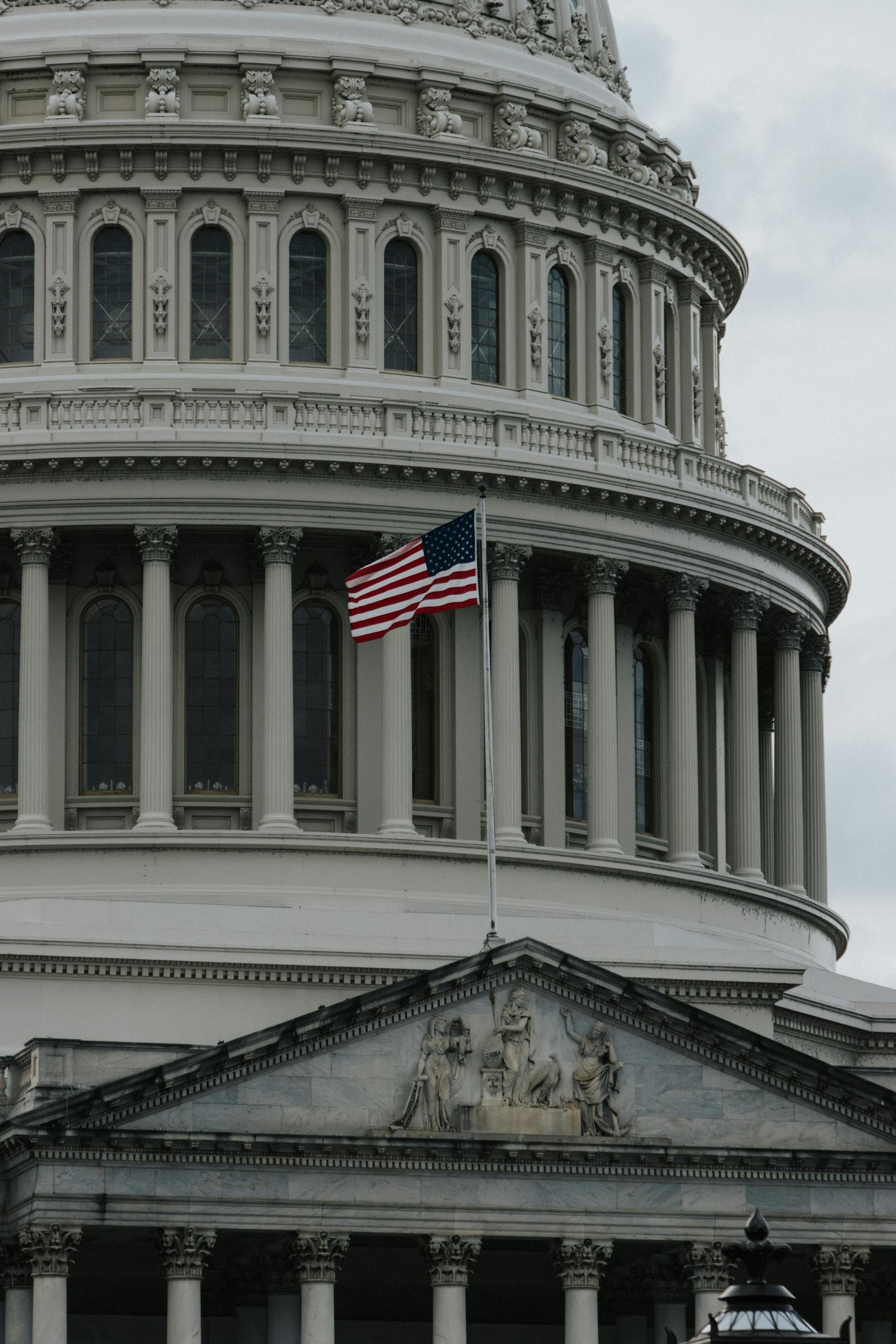 Close-up of the United States Capitol with American flag waving outside.