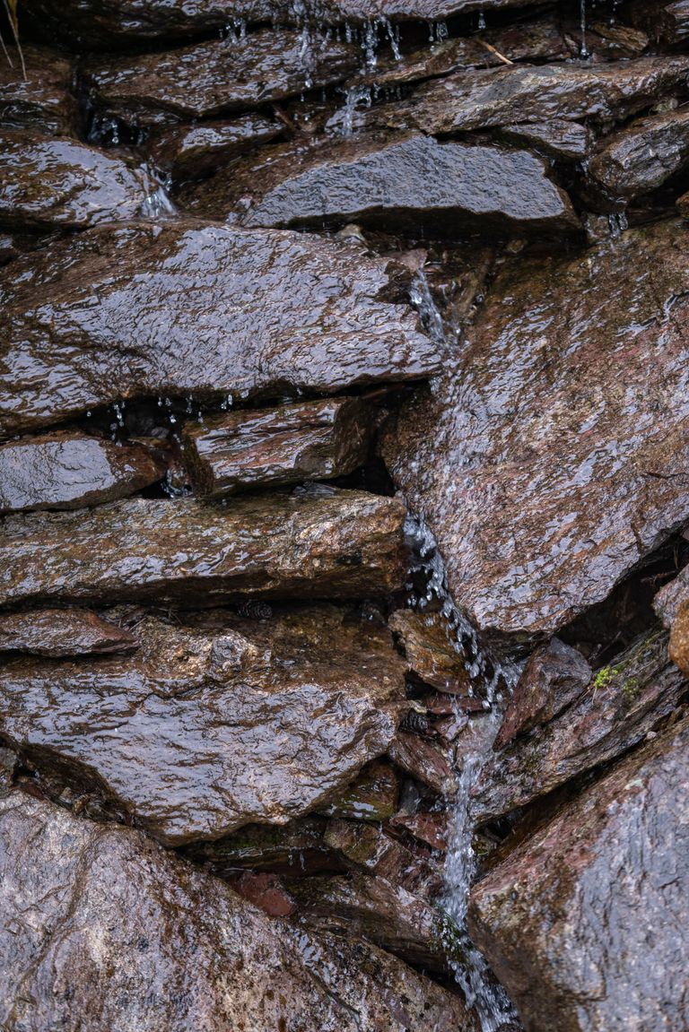 Close-up of wet rocks with water trickling down their surface creating a natural pattern.