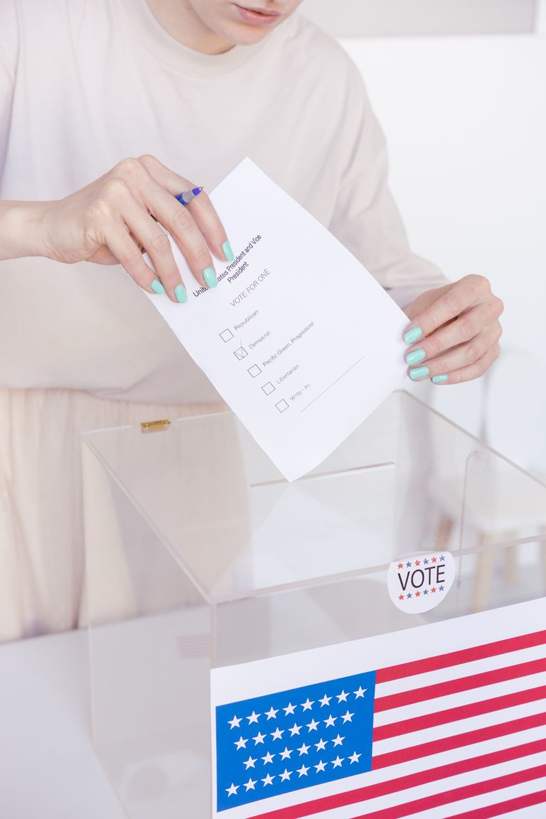 A person casting a vote in a transparent ballot box during an election.