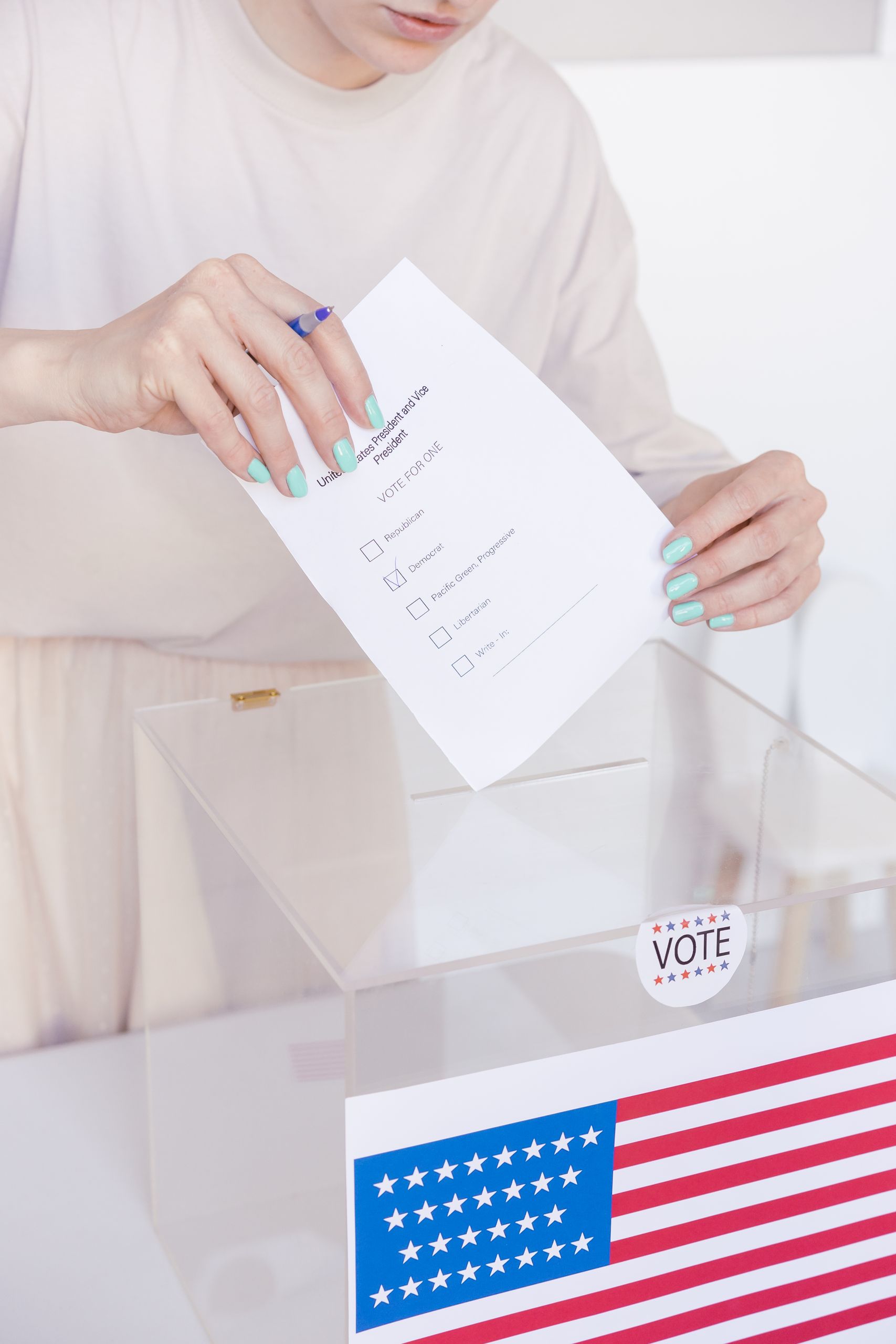 A person casting a vote in a transparent ballot box during an election.