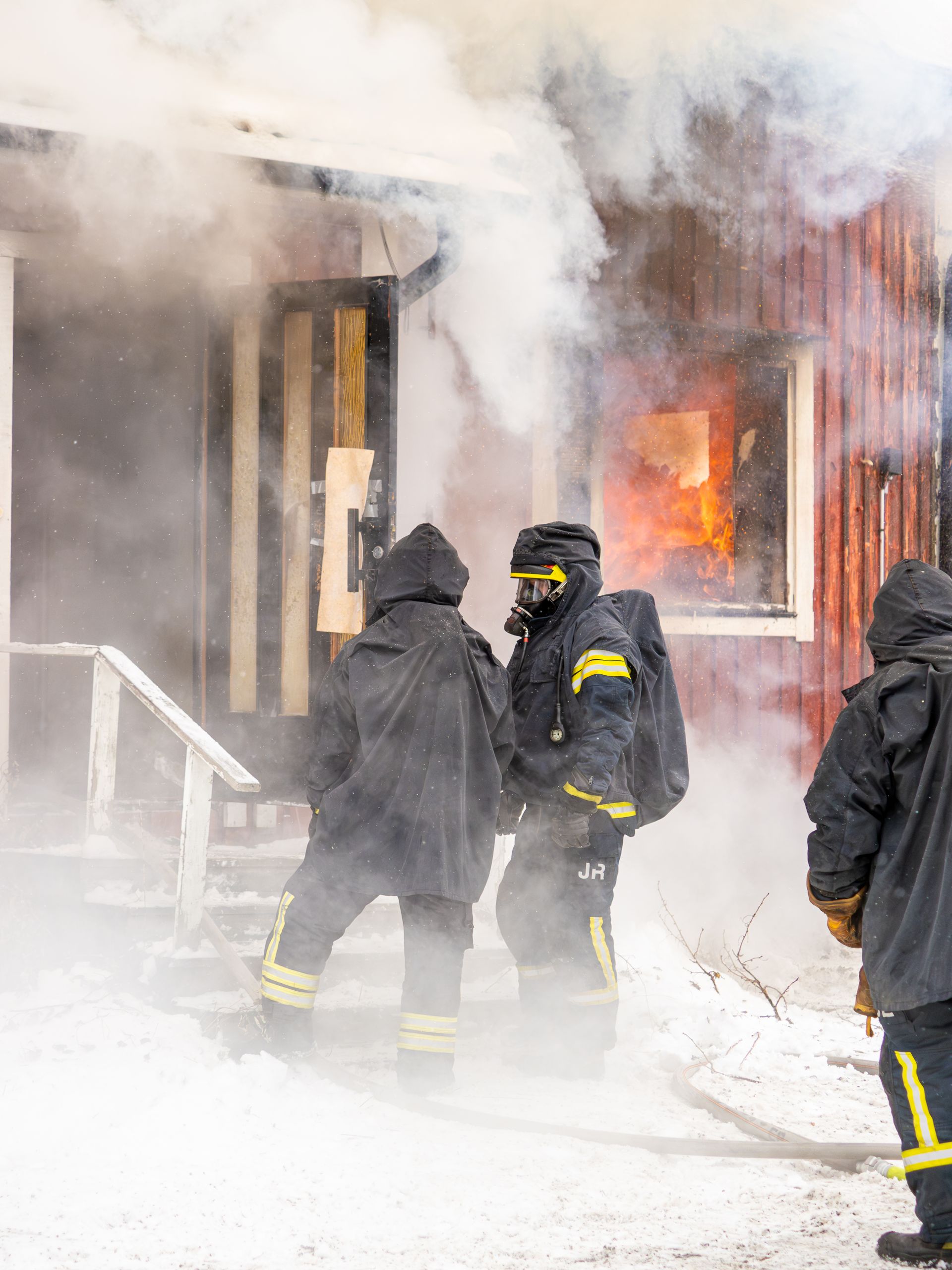 Firefighters extinguishing a blaze in a snowy residential area, showcasing winter rescue efforts.