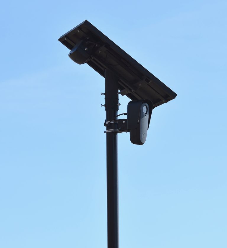 A solar-powered surveillance camera on a pole against a clear blue sky, ideal for monitoring.