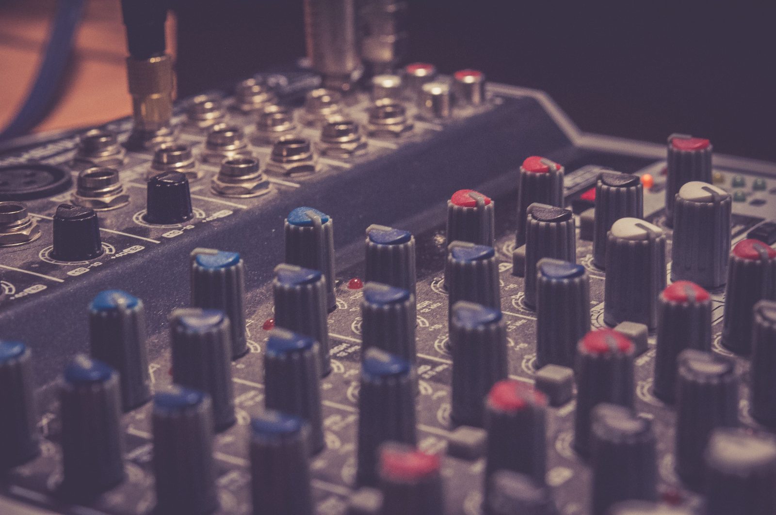 Stock photo for illustration: Detailed view of a professional audio mixer in a music studio, highlighting control knobs and switches.
