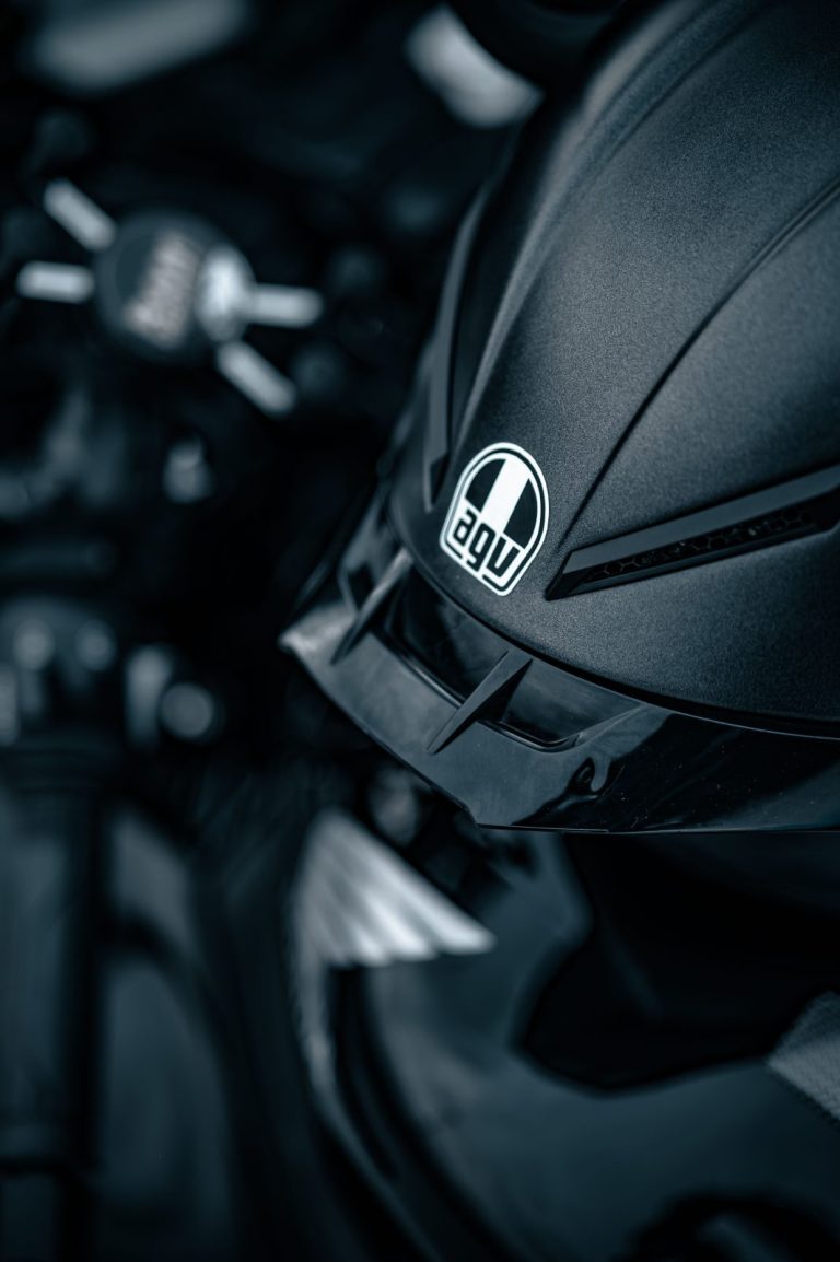 Stock photo for illustration: Detailed image of a sleek black motorcycle helmet and part of a motorcycle.