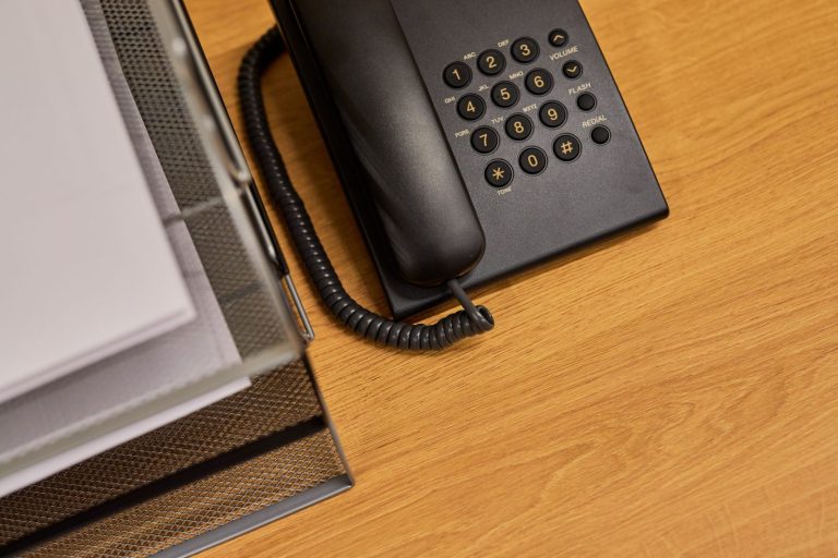 Stock photo for illustration: A tidy office desk featuring a classic black telephone and organized documents.